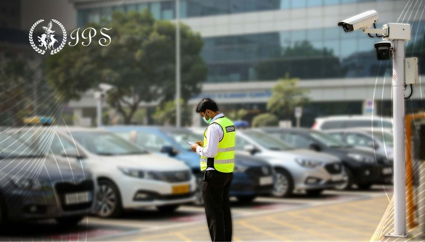 Security guard monitoring a parking space with CCTV cameras and parked cars.